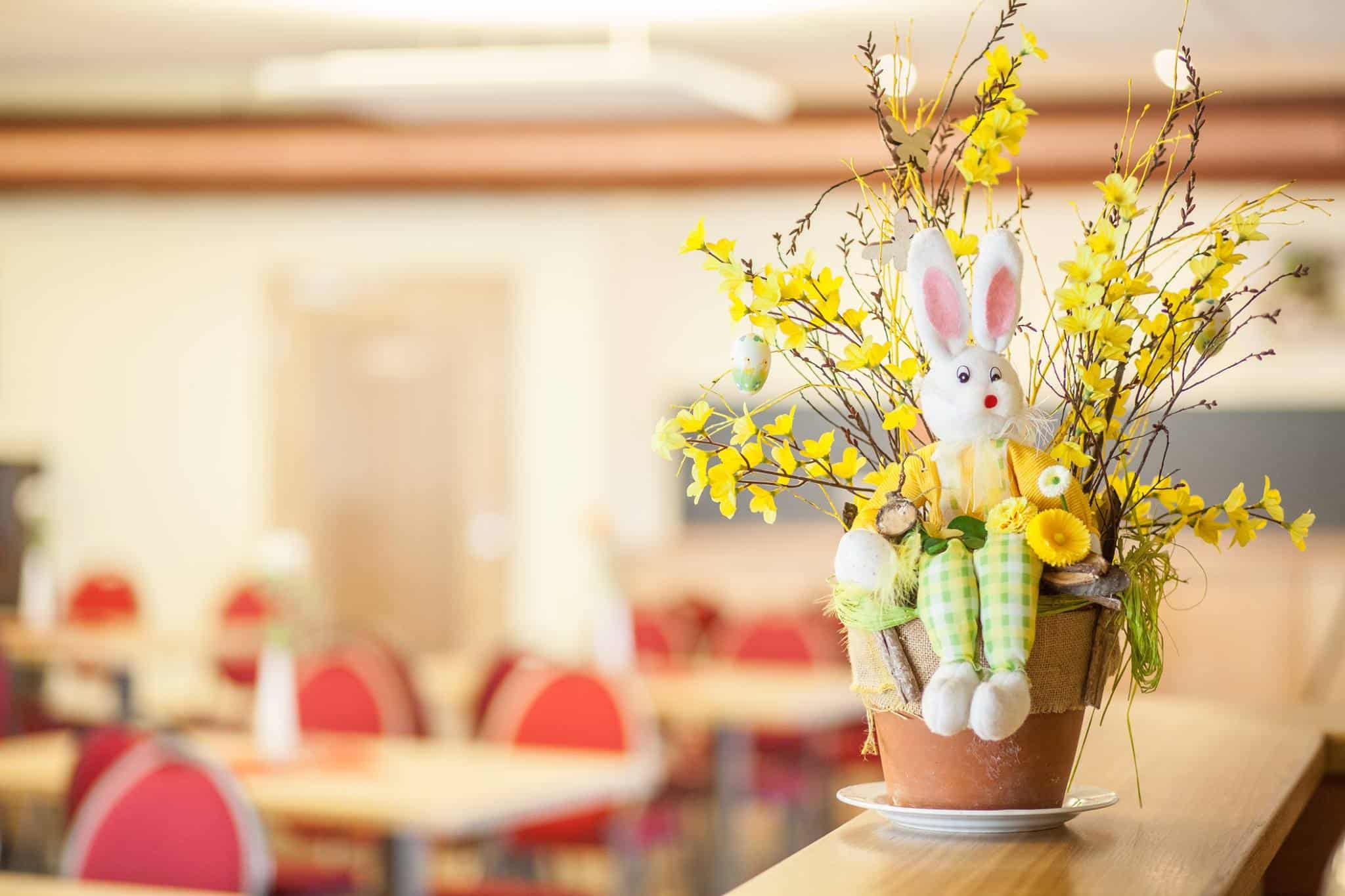 Ostergesteck mit Hase und Forsythienzweigen auf einem Tisch im Gastraum