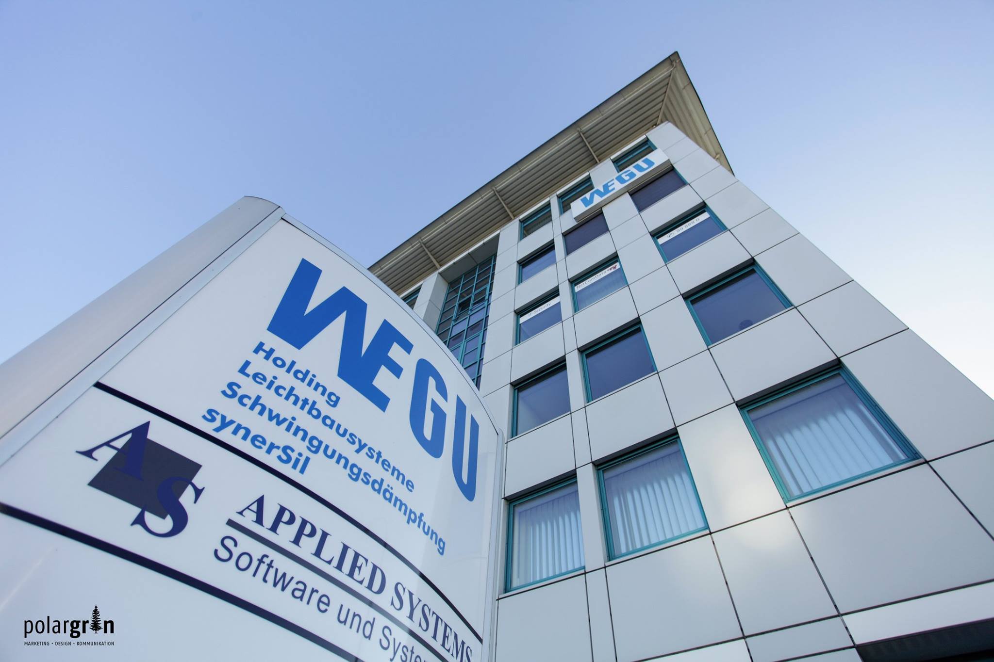 Firmenschild von WEGU vor einem Bürogebäude, von unten fotografiert