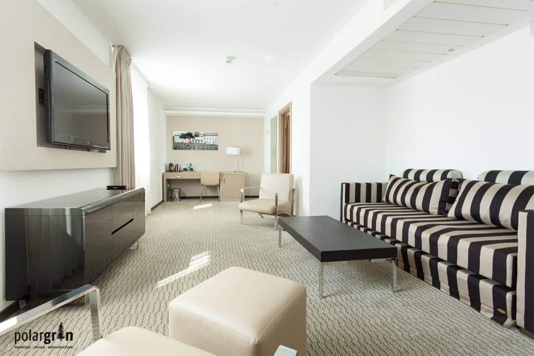 Lounge mit gestreifter Sitzbank, Sesseln und Fernseher an der Wand