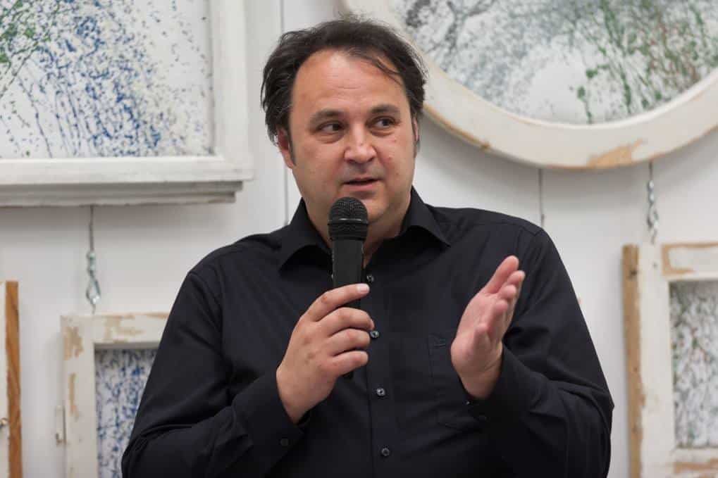 Redner mit Mikrofon bei der Eröffnung einer Ausstellung