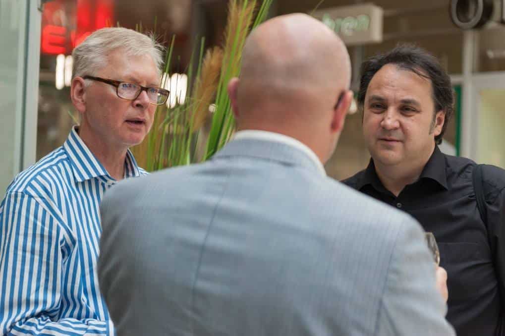Drei Besucher im Gespräch bei einer Vernissage
